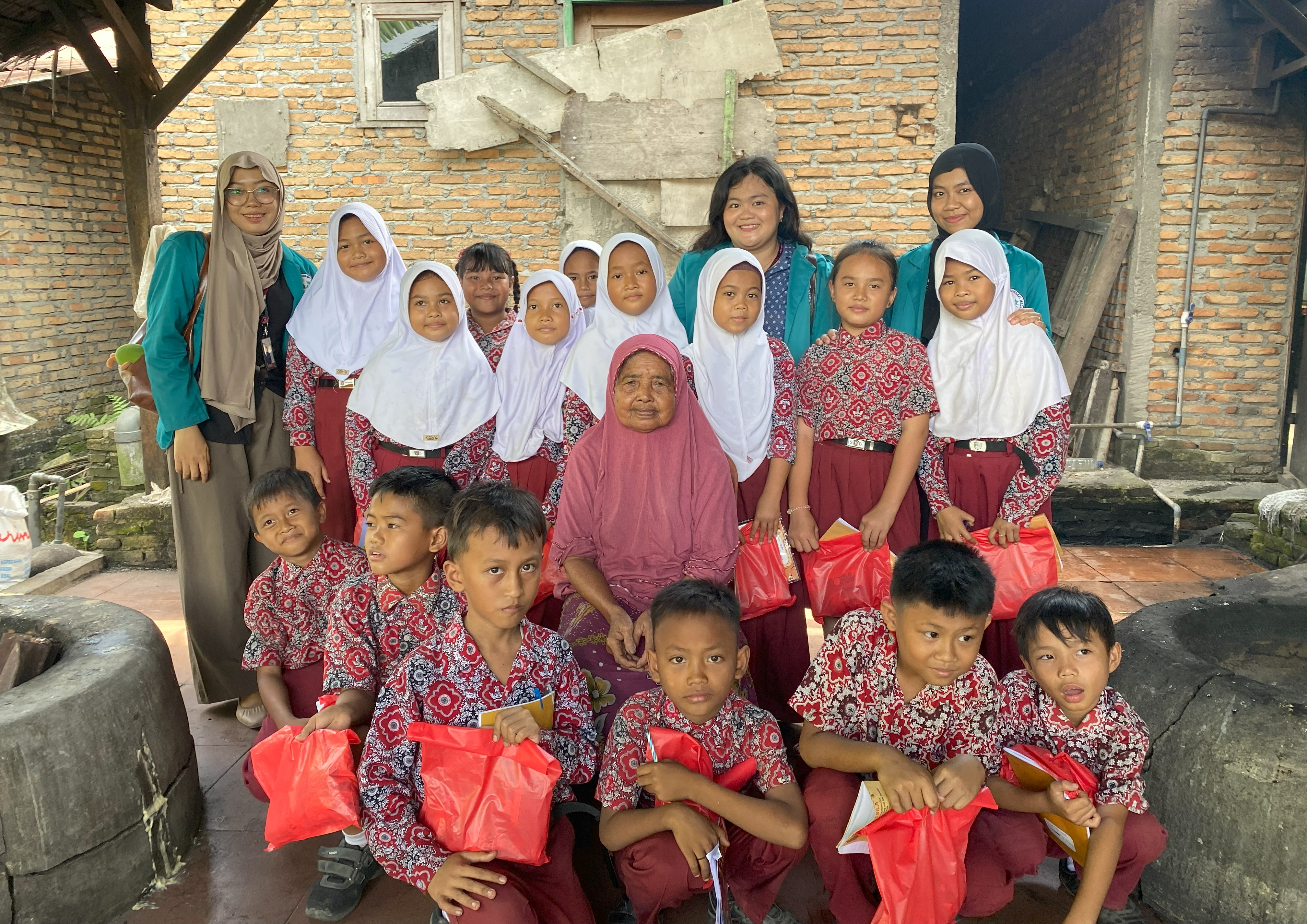 Foto bersama Nenek Irup, pemilik usaha Dodol Raudah bersama Mahasiswa KKN Unimed 2025 dan Siswa SDN 101942 setelah pelaksanaan Program Kerja Study Outdoor Pembuatan Dodol